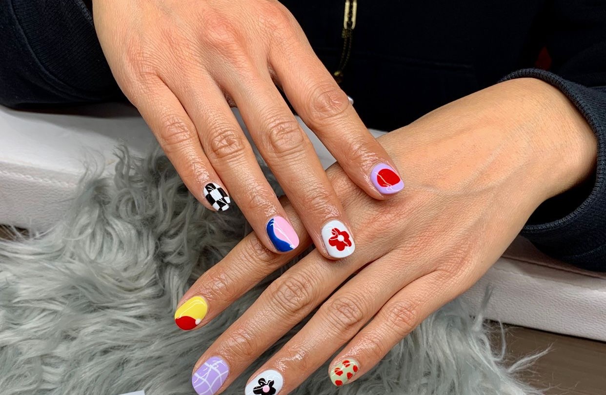 Korte nagels met kleurige nail art, elke nagel een ander ontwerp: ruitjes, bloemetjes en stippen