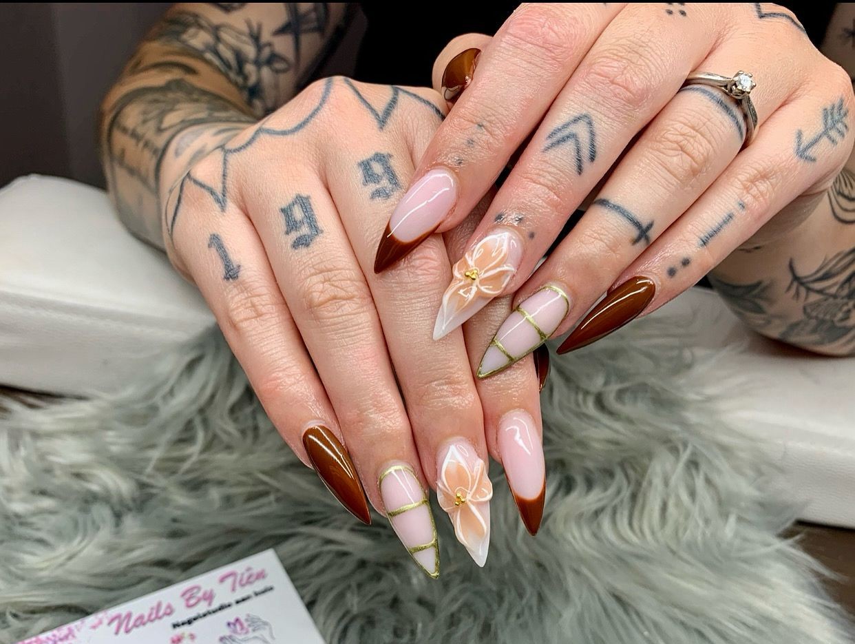 Lange amandelvormige nagels met een bloem in 3D, gouden lijnen en bruine accenten
