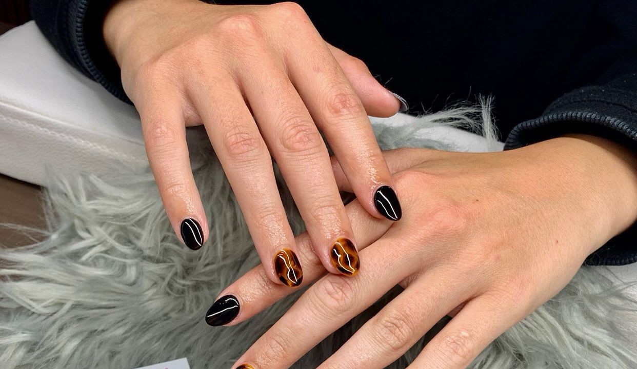Korte nagels in zwart en schildpad, op een grijs vachtje